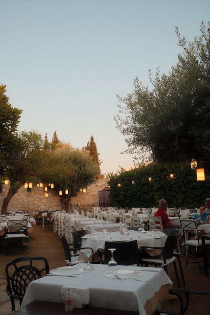 A cozy outdoor restaurant setting with tables and lanterns during twilight.